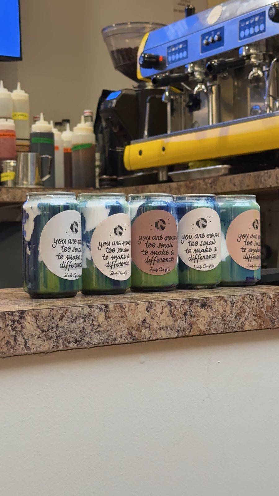 Custom-labeled cans lined up in front of the espresso machine