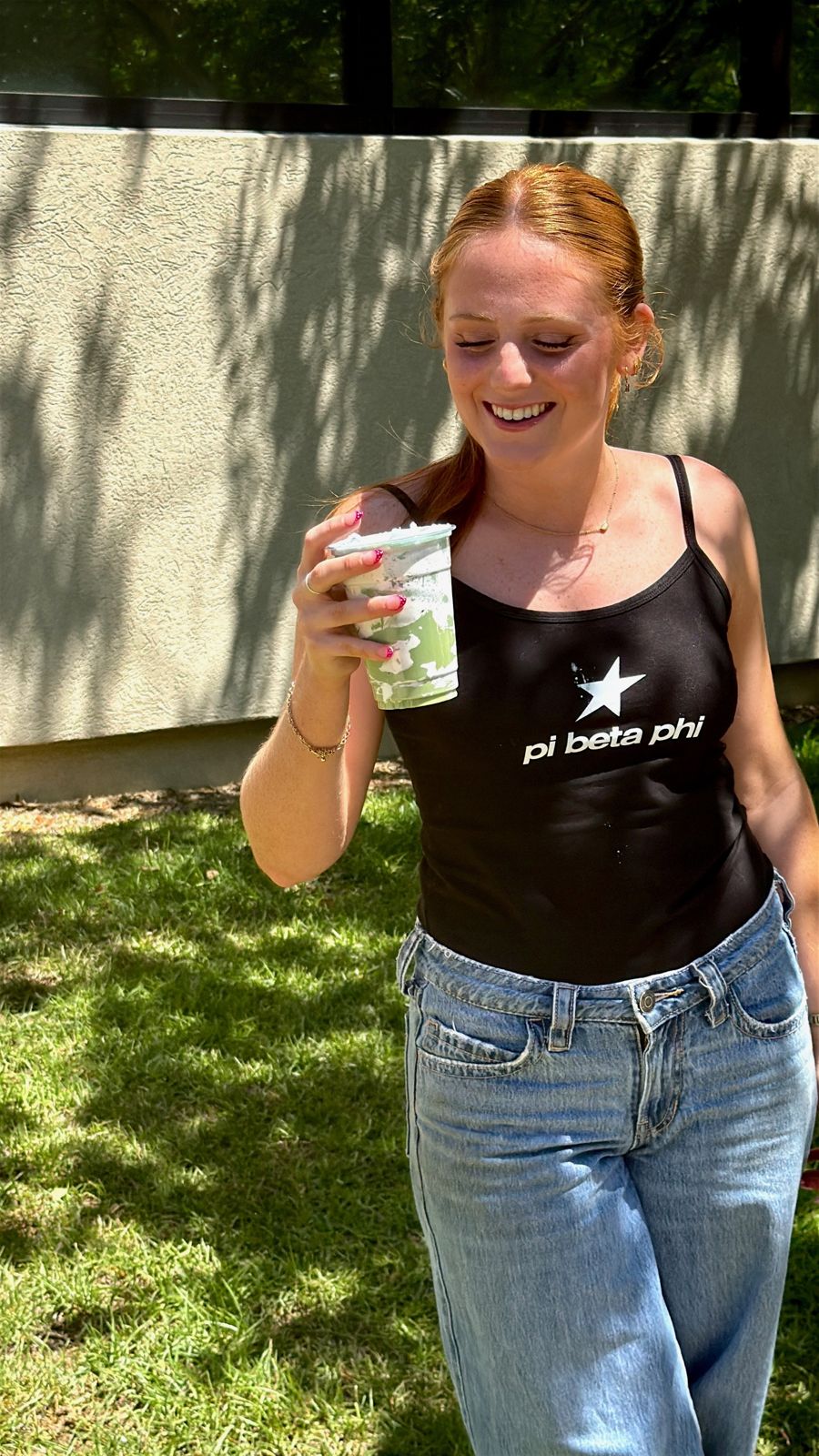 A customer laughing with her iced latte outside